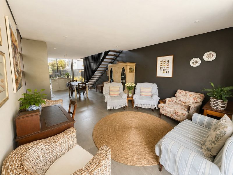 Spacious open-plan living area featuring tiled flooring, recessed lighting, and a modern staircase, flowing seamlessly into the kitchen space.
