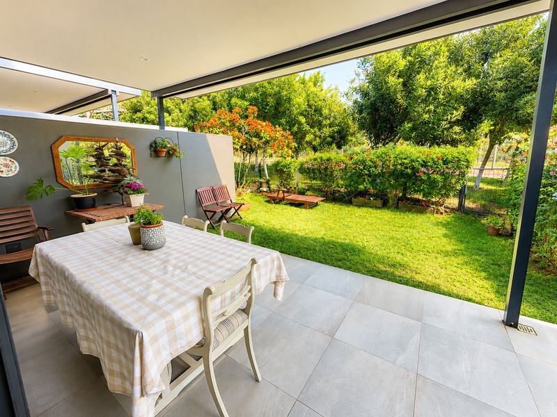 A well-maintained covered patio featuring large format floor tiles, recessed lighting, and direct access to a landscaped private garden.