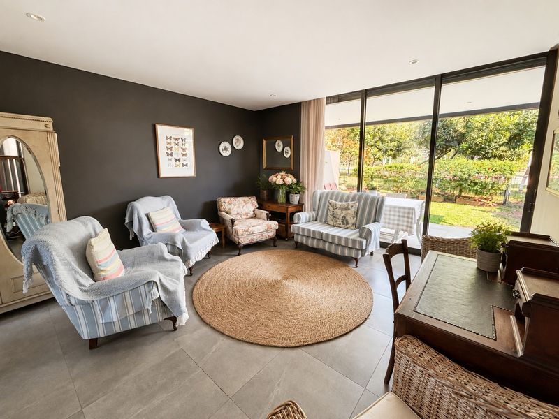 A bright living room featuring large sliding glass doors that provide seamless access to the garden and patio area, complemented by modern tiled flooring.