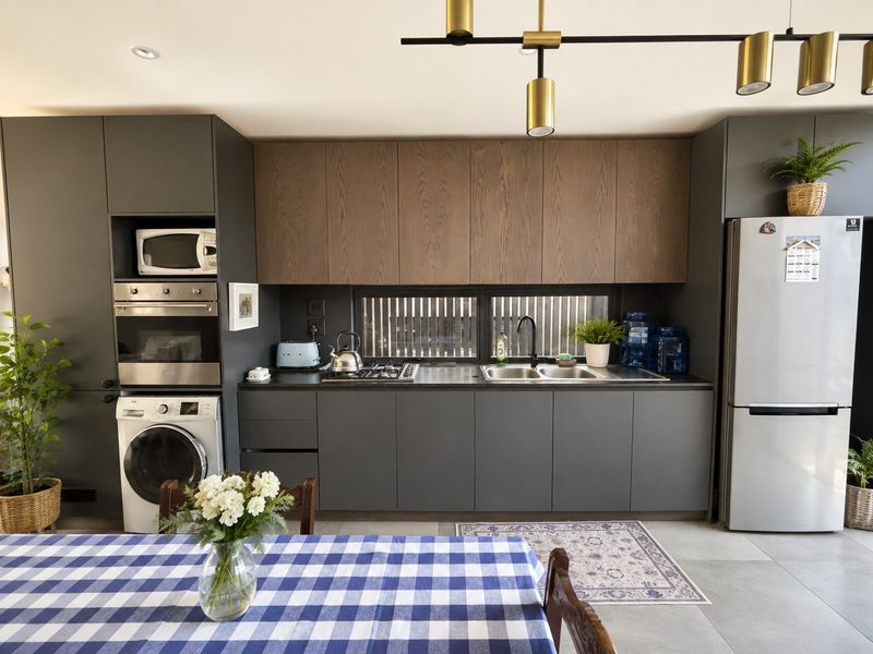 Modern kitchen featuring dark grey cabinetry, wood-tone upper cabinets, built-in oven and microwave, gas hob, and double sink with contemporary lighting.