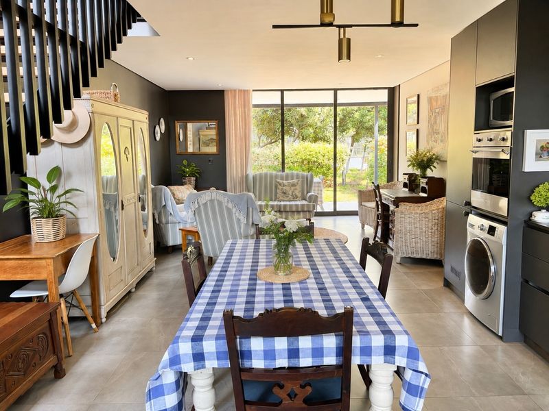 Spacious open-plan living and dining area featuring modern cabinetry, integrated appliances, tiled floors, and large sliding doors leading to the garden.