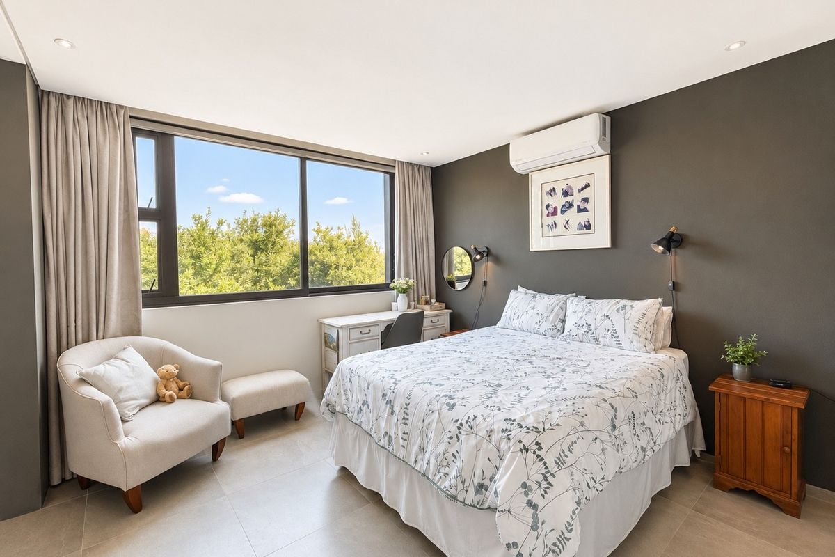 A well-lit bedroom featuring large windows, tiled flooring, a wall-mounted air conditioning unit, and modern recessed lighting.