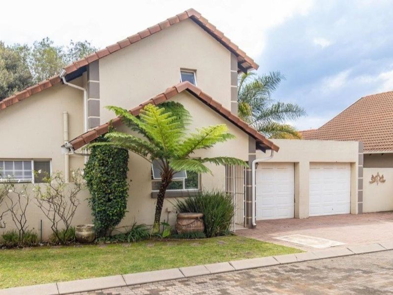 A well-maintained double-story residential home featuring a double garage, paved driveway, and established front garden.