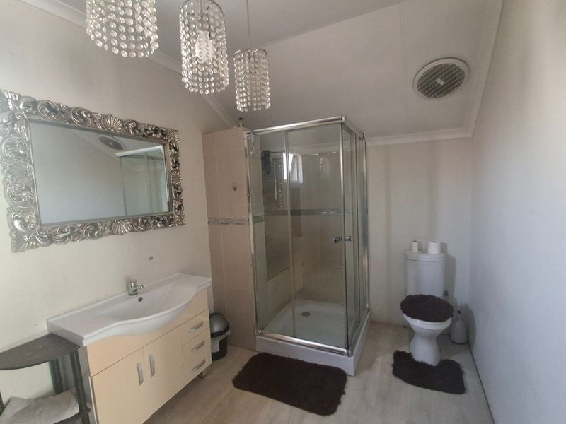 A functional bathroom featuring a vanity cabinet with basin, a glass shower enclosure, and a standard toilet.