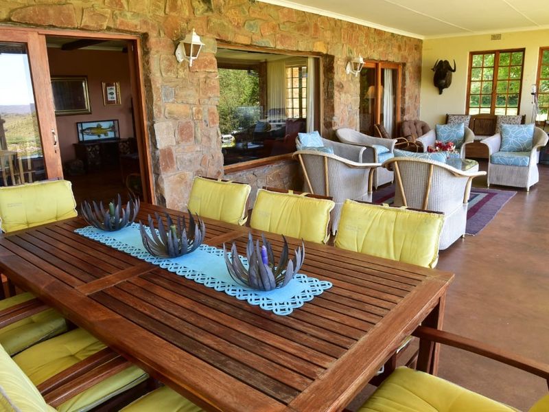 A spacious covered patio featuring rustic stone wall cladding, concrete flooring, and large sliding glass doors providing seamless access to the interior living areas.