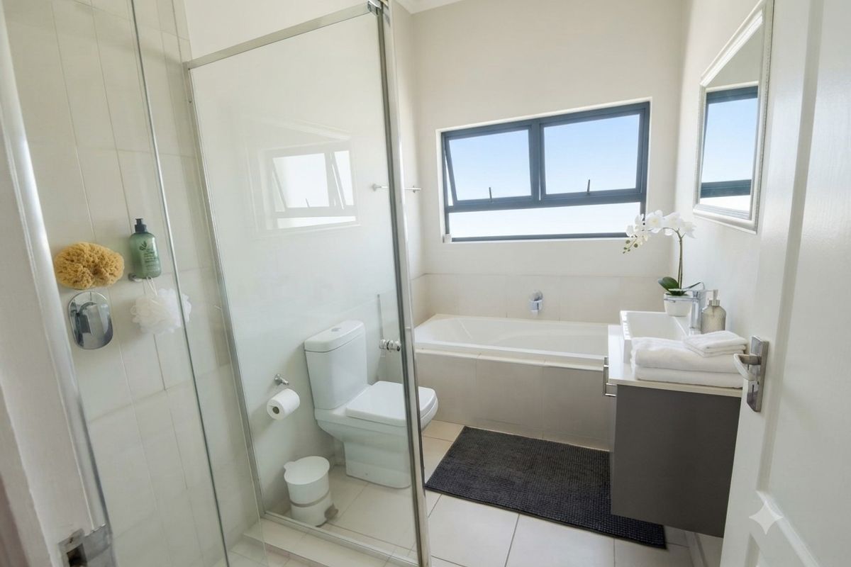 Modern bathroom featuring a glass-enclosed shower, a built-in bathtub, a wall-mounted toilet, and a sleek vanity cabinet with tiled flooring.