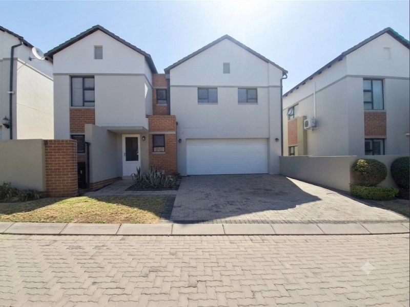 Front elevation of a modern two-storey residential house featuring a paved driveway, double garage, and brick boundary walling.