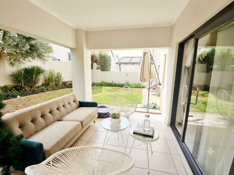 A covered patio area featuring tiled flooring and large sliding glass doors, providing seamless access to the private garden space.