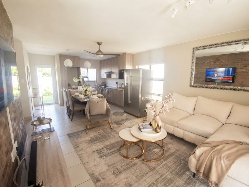 Spacious open-plan living and kitchen area featuring tiled floors, modern cabinetry, and an exposed brick feature wall, creating a bright and functional living space.