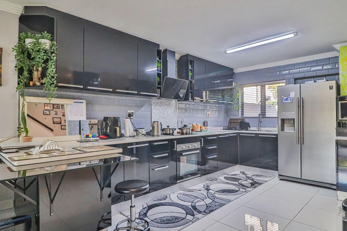 Modern kitchen featuring high-gloss black cabinetry, subway tile backsplash, built-in oven, extractor fan, and polished porcelain floor tiles.