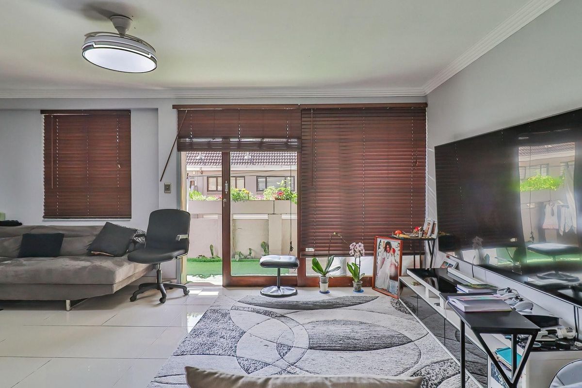 A bright living room featuring tiled flooring, a ceiling fan, and sliding glass doors that provide direct access to the outdoor patio area.