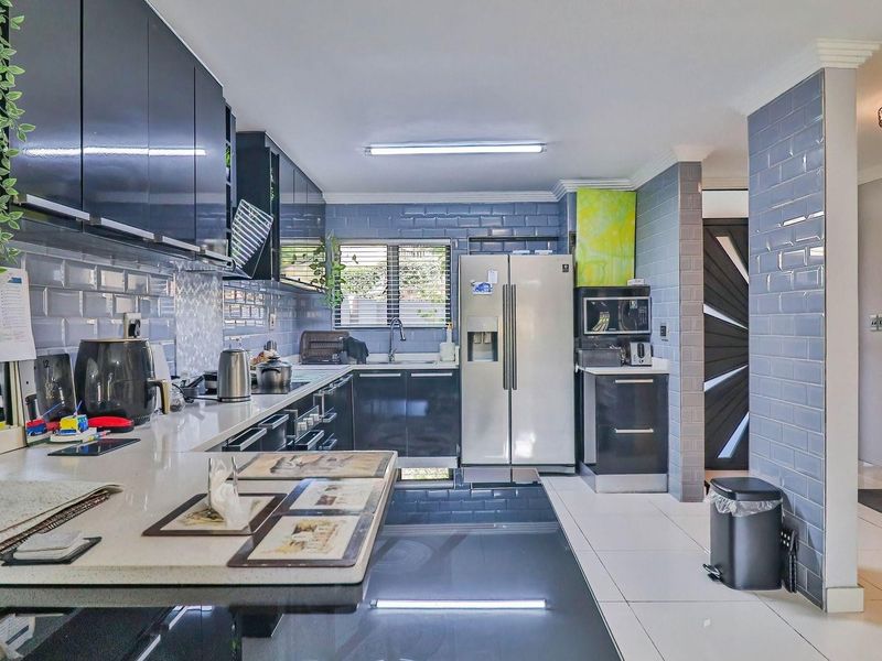 Modern kitchen featuring high-gloss cabinetry, quartz countertops, subway tile backsplash, and integrated appliances with a clean, contemporary aesthetic.