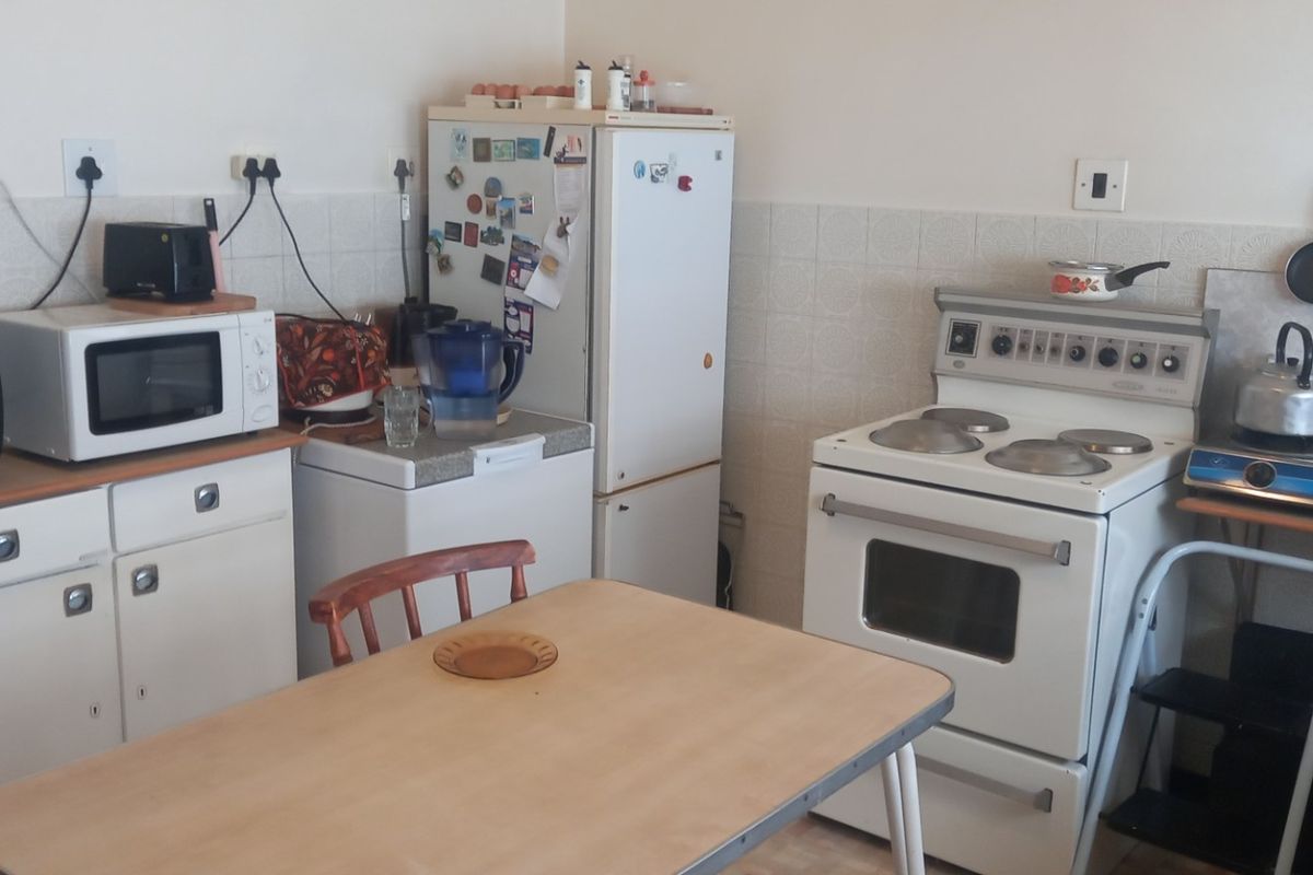 A functional kitchen featuring white cabinetry, a tiled splashback, and a freestanding stove, offering potential for modernization and layout optimization.