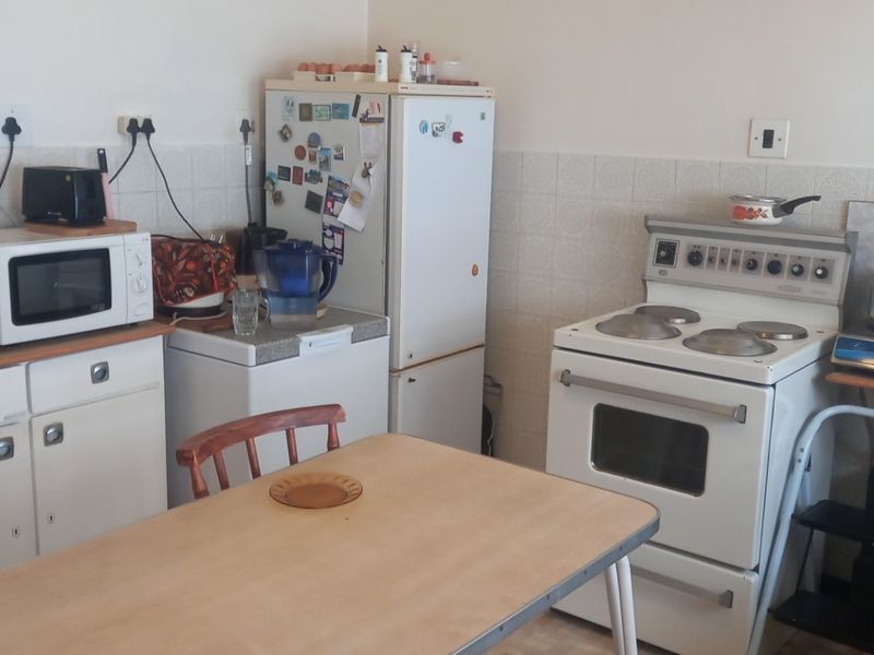 A functional kitchen featuring white cabinetry, a tiled splashback, and a freestanding stove, offering potential for modernization and layout optimization.
