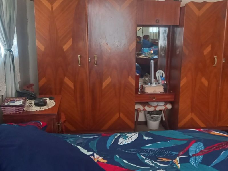 A bedroom featuring a large built-in wooden wardrobe unit with integrated vanity and mirror.