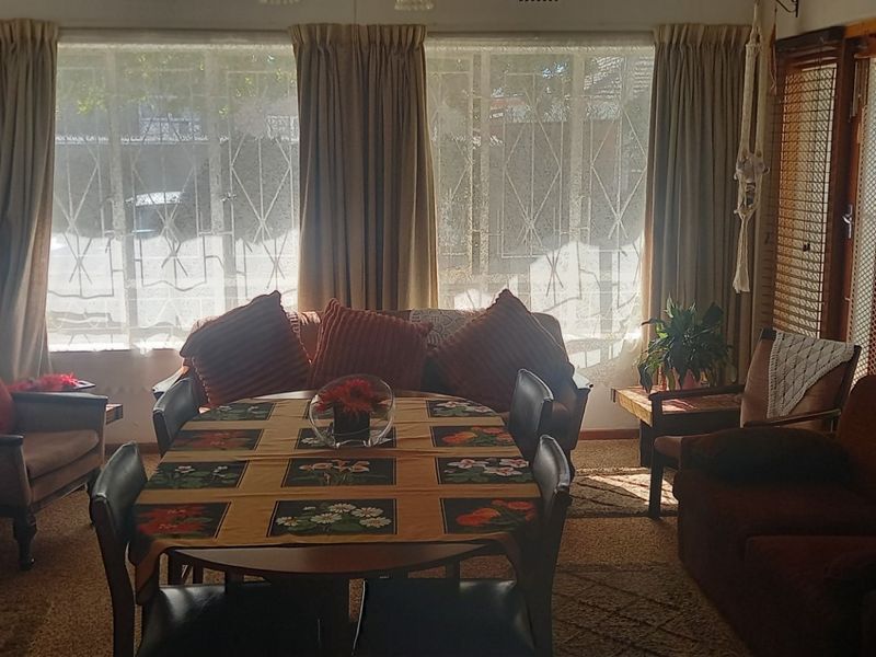 A living room featuring a fireplace and large windows with security bars, offering a functional space with potential for modernization.