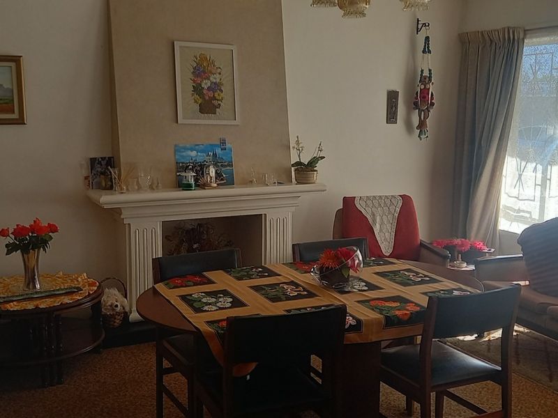 A traditional living room featuring a central fireplace with a decorative mantelpiece and large windows fitted with security gates.