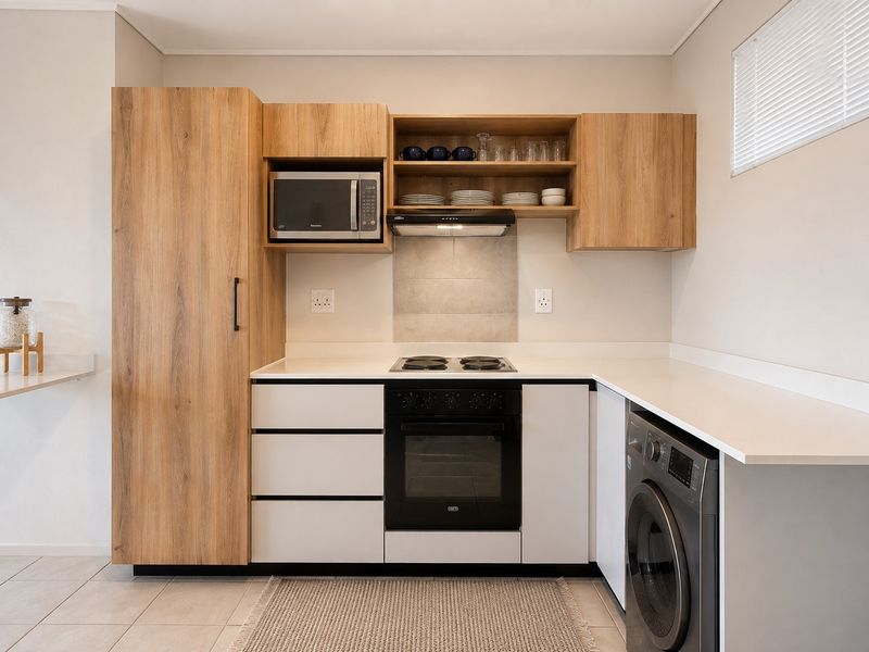 Modern kitchen featuring wood-look cabinetry, white countertops, built-in oven, hob, extractor fan, and integrated microwave with a clean, contemporary finish.
