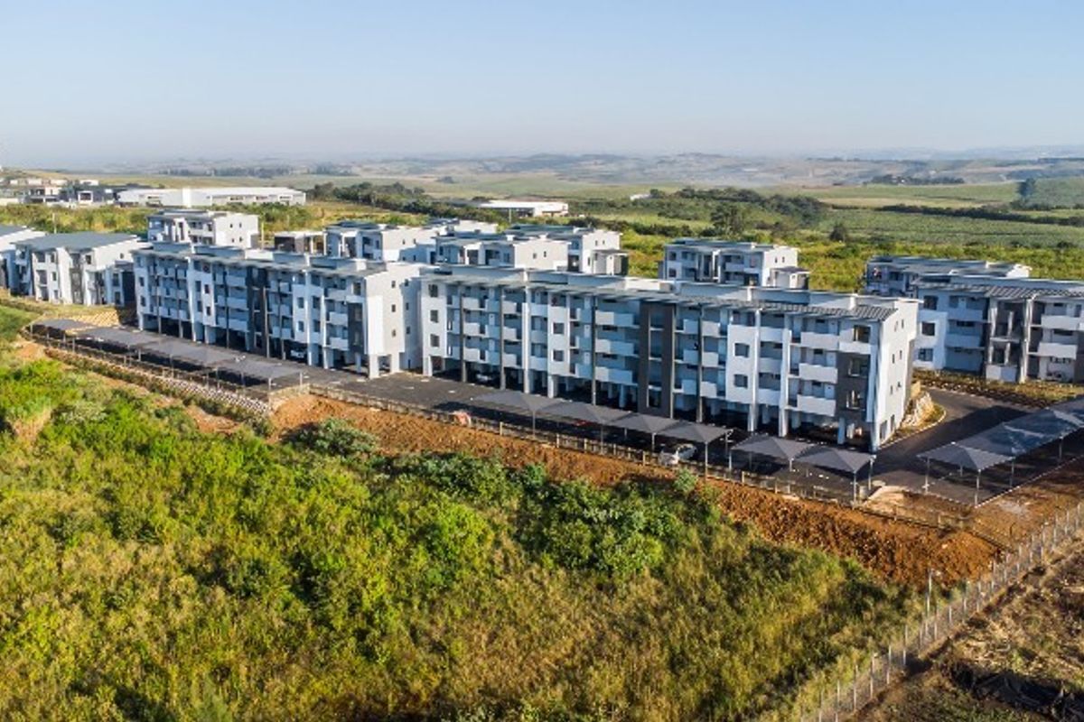 Aerial view of a modern multi-story apartment complex featuring covered parking bays and surrounding landscaped grounds.