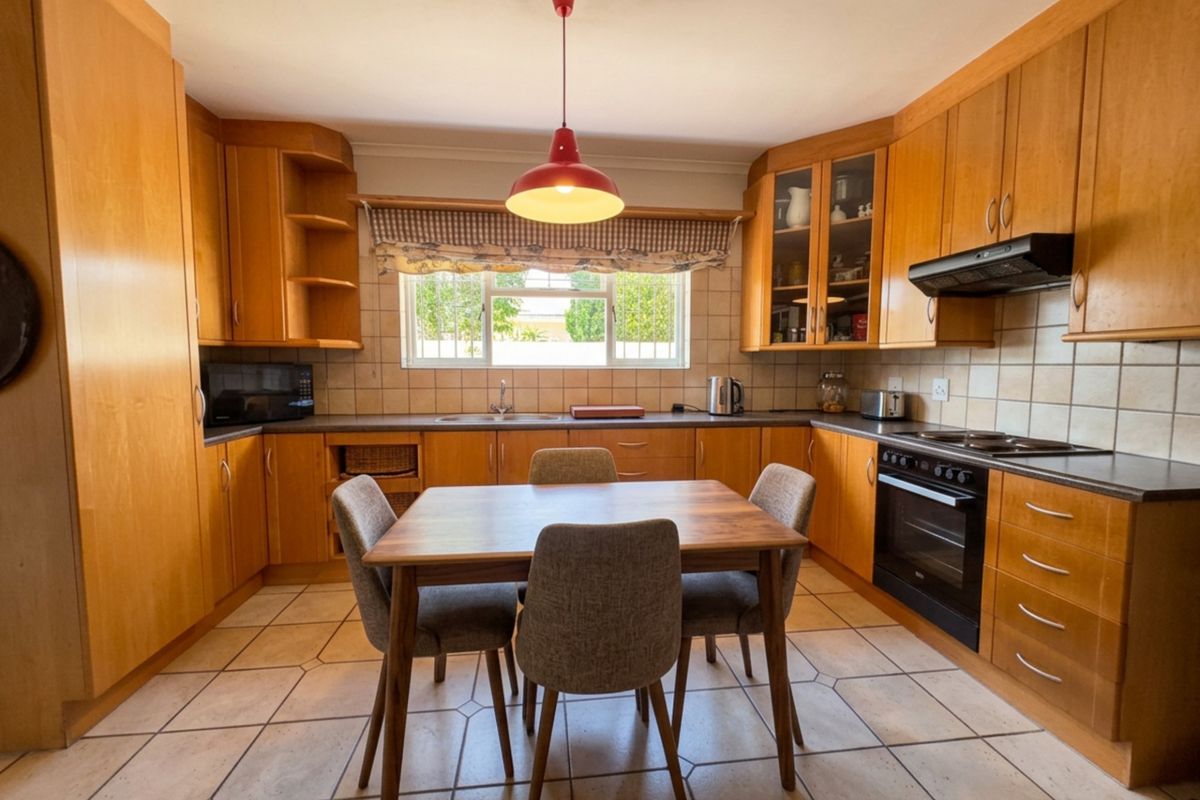 A functional kitchen featuring wooden cabinetry, tiled flooring, built-in oven, hob, and extractor fan, with a central dining area.