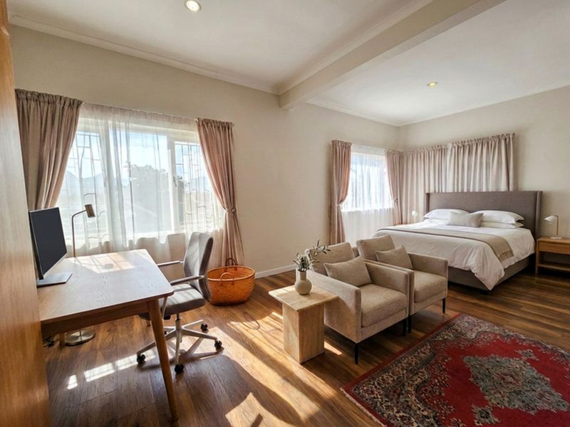 Spacious bedroom featuring timber flooring, recessed downlighting, and large windows with security bars, offering a bright and comfortable living space.