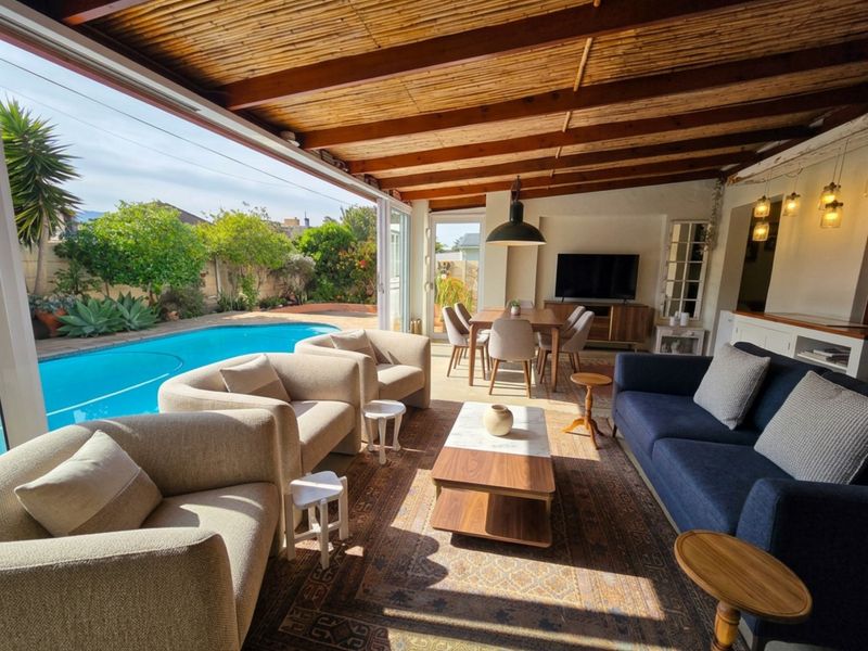 Spacious open-plan living area featuring exposed timber beam ceilings and seamless indoor-outdoor flow to a private swimming pool and patio.