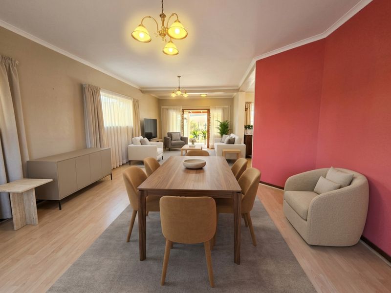 Spacious open-plan living and dining area featuring laminate flooring, neutral walls with a bold accent wall, and direct access to the outdoor patio.