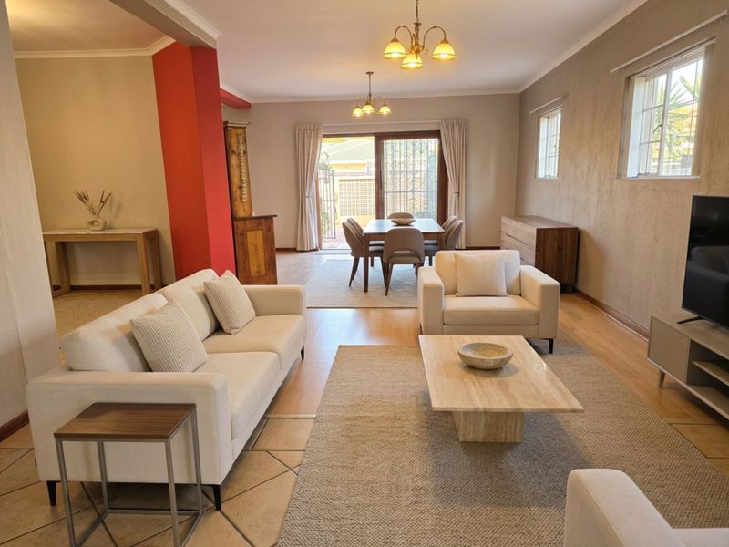 Spacious open-plan living and dining area featuring a mix of tiled and laminate flooring, with direct access to the rear patio through sliding doors.