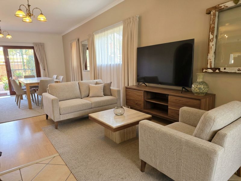 Spacious open-plan living and dining area featuring laminate flooring, neutral walls, and sliding glass doors providing access to the outdoor patio.