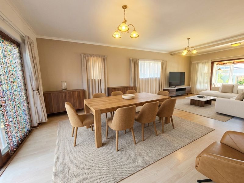 Spacious open-plan living and dining area featuring light laminate flooring, neutral walls, and large sliding glass doors providing ample natural light.