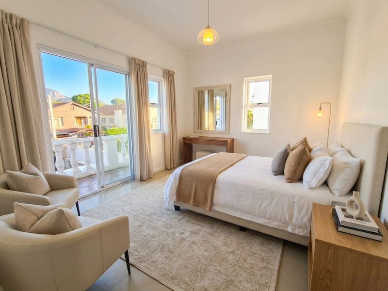 A bright, well-maintained bedroom featuring neutral tones, a sliding glass door leading to a private balcony, and ample natural light.