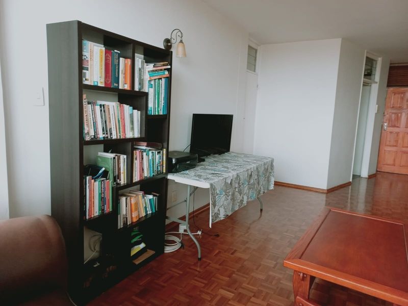 A living room area featuring classic parquet flooring and a solid timber door, providing a neutral foundation for interior updates.