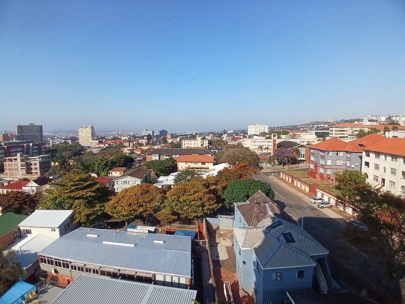 An elevated panoramic view overlooking the surrounding urban neighborhood, residential buildings, and tree-lined streets.