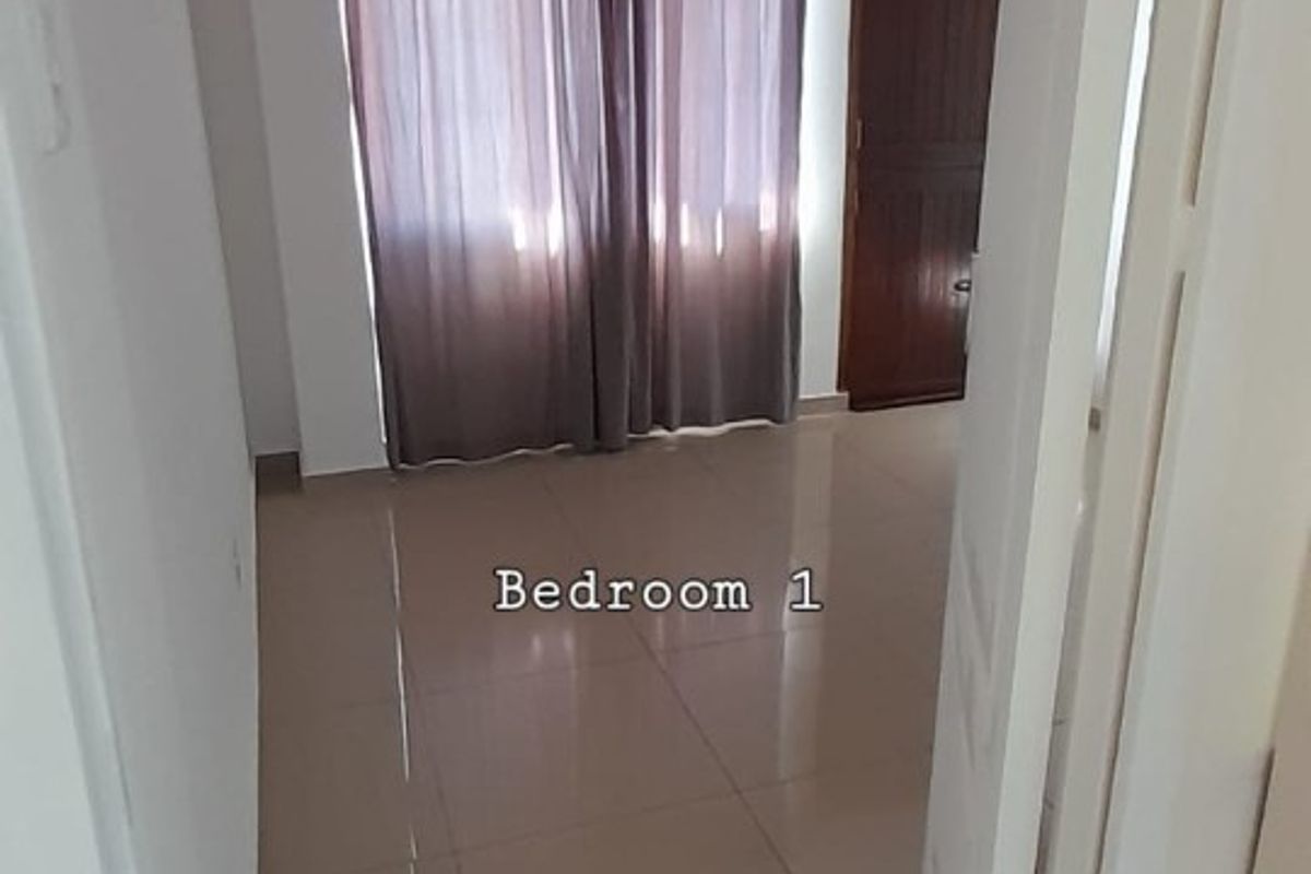 An empty bedroom featuring neutral tiled flooring and a standard internal door, offering a blank canvas for personalization.