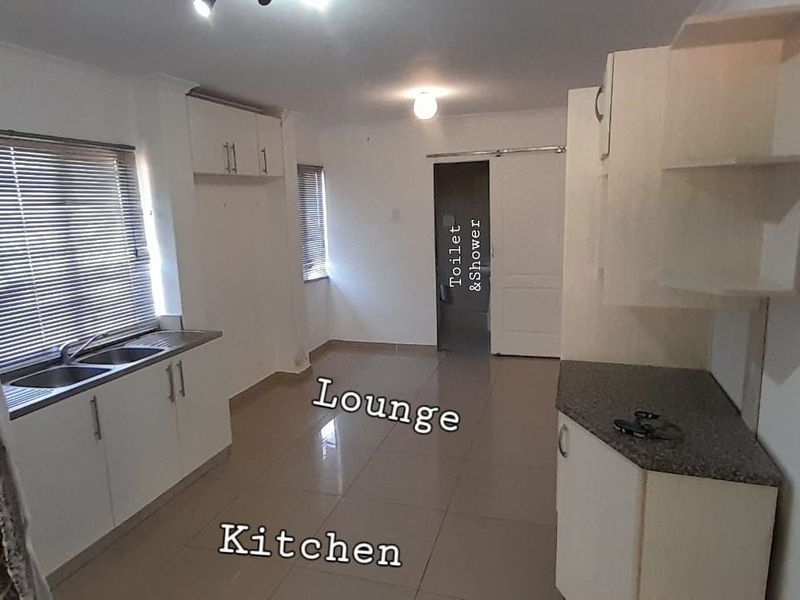 Open plan kitchen and living area featuring tiled floors, built-in cabinetry, and double sink, providing a functional and versatile living space.