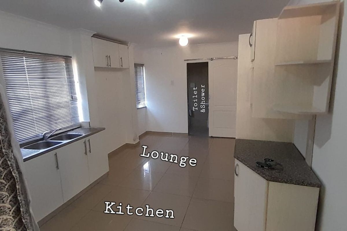 Open plan kitchen and living area featuring tiled floors, built-in cabinetry, and double sink, providing a functional and versatile living space.