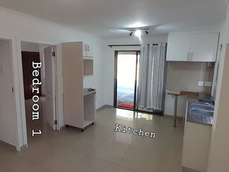 Open plan living and kitchen area featuring tiled floors, built-in cabinetry, and direct access to an outdoor space via a sliding glass door.
