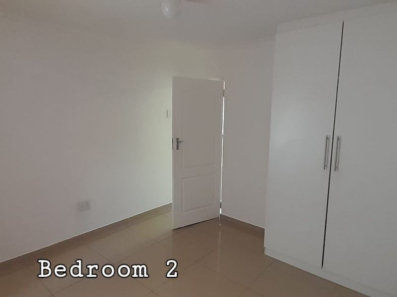 A clean, empty bedroom featuring neutral tiled flooring and a built-in white wardrobe, offering a blank canvas for personalization.