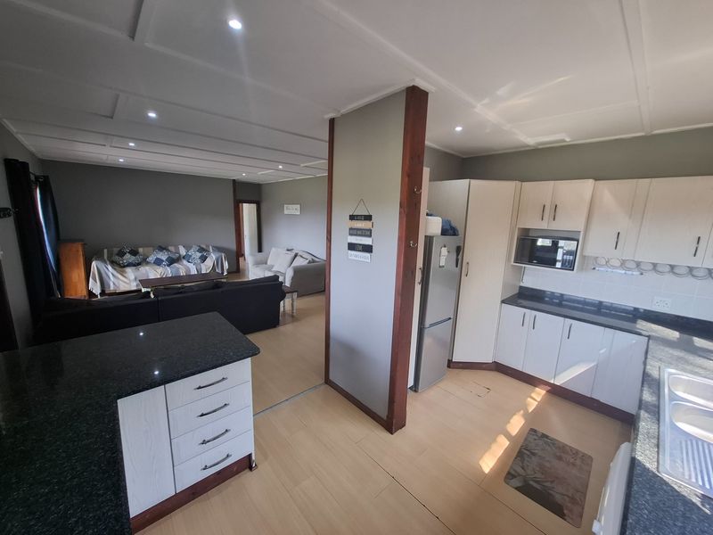 Open-plan living area featuring a modern kitchen with granite countertops, built-in cabinetry, and integrated appliances, flowing into a spacious lounge area.