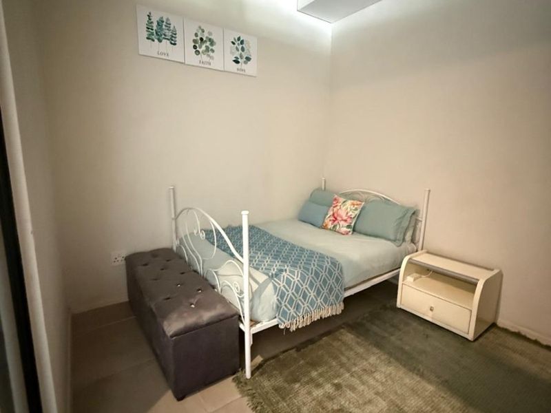 A bedroom featuring an industrial-style exposed concrete ceiling and neutral tiled flooring, providing a clean and modern foundation for the space.
