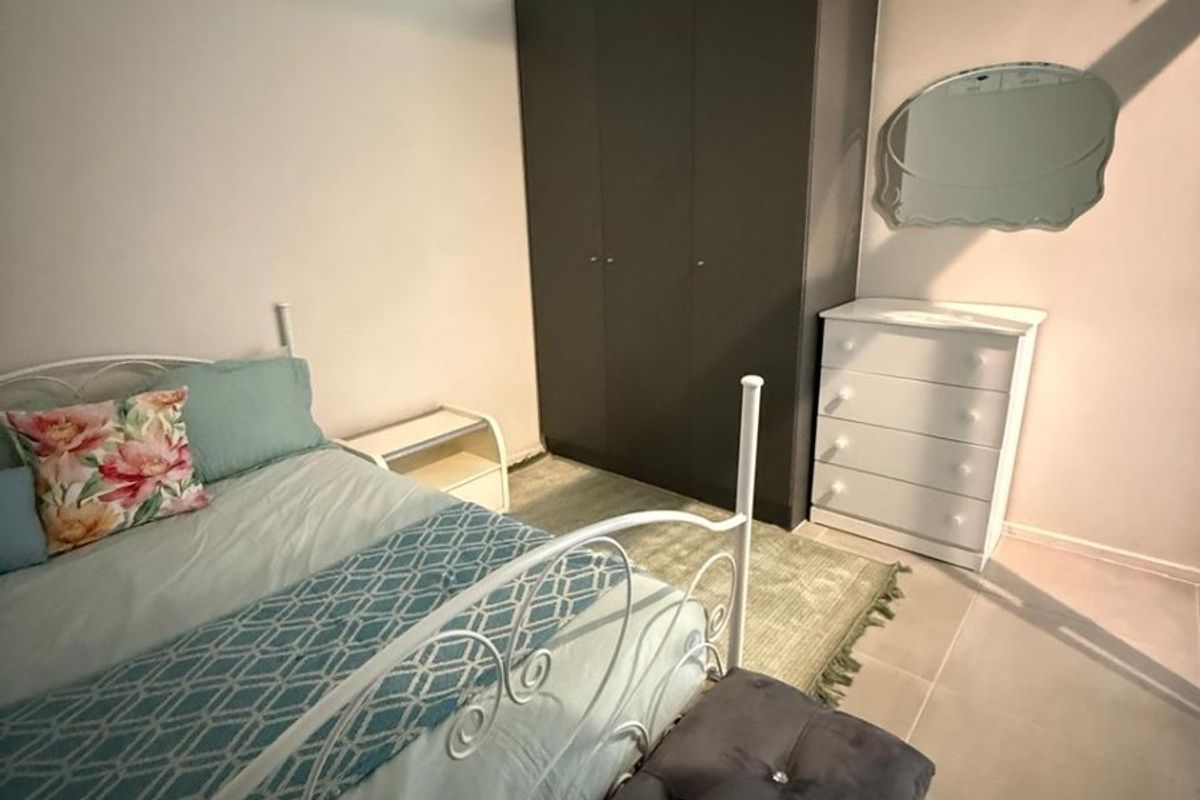 A bedroom featuring a built-in wardrobe, tiled flooring, and a high-level clerestory window providing natural light.