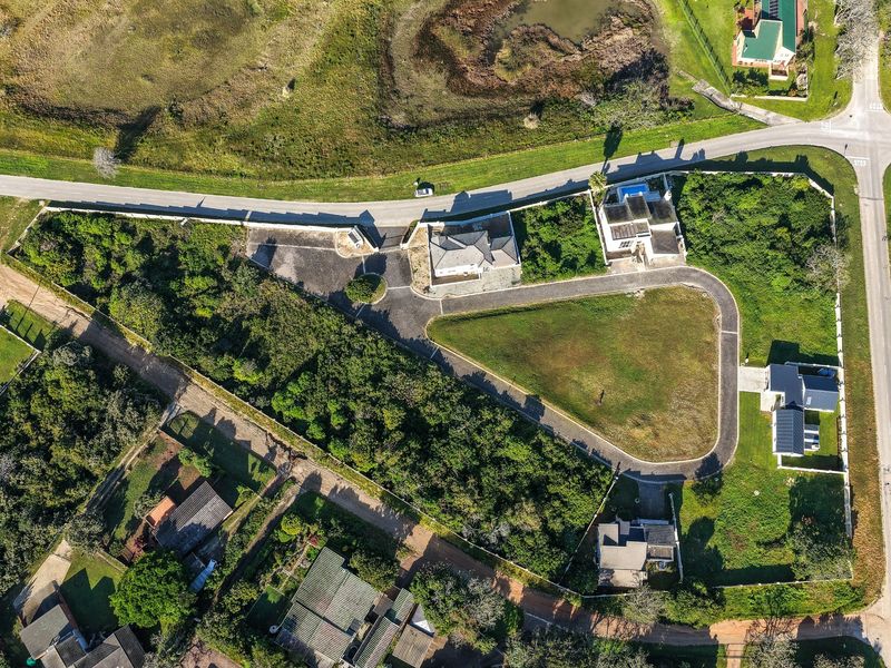Aerial view of a vacant residential land plot featuring a paved driveway and established boundary fencing within a developed neighborhood.