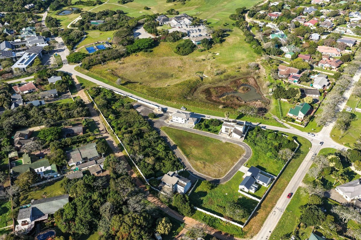 Aerial view of a residential development area featuring vacant plots, paved access roads, and established perimeter fencing within a landscaped estate setting.