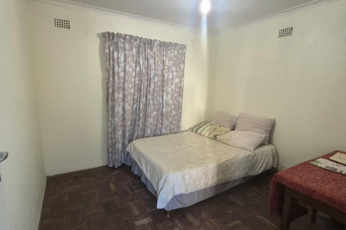 A simple bedroom featuring parquet flooring and neutral walls, providing a functional space with basic finishes.