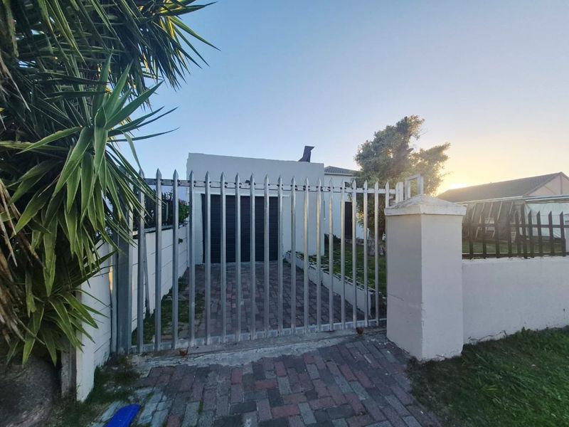 Front view of the townhouse featuring a secure metal gate, paved driveway, and garage access.