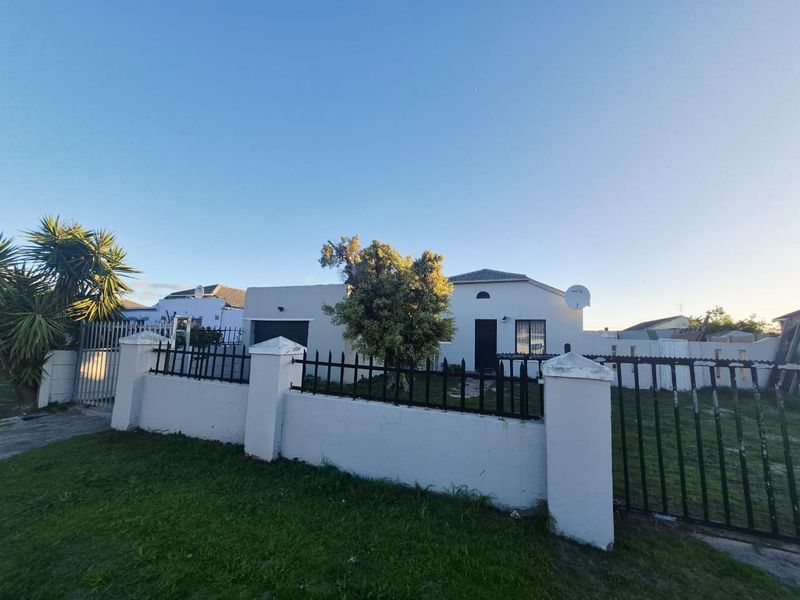 Front exterior view of a townhouse featuring a perimeter wall with metal fencing, a garage, and a paved entrance area.