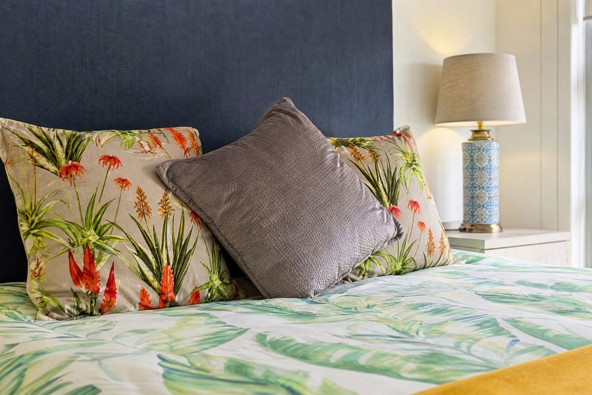 A close-up view of a bedroom featuring a dark blue upholstered headboard and a modern aluminium window frame.