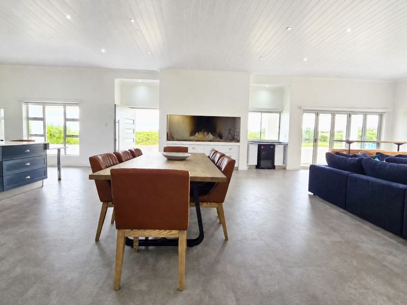 Spacious open-plan living and dining area featuring a built-in fireplace, modern kitchen cabinetry, and large sliding doors leading to the exterior.