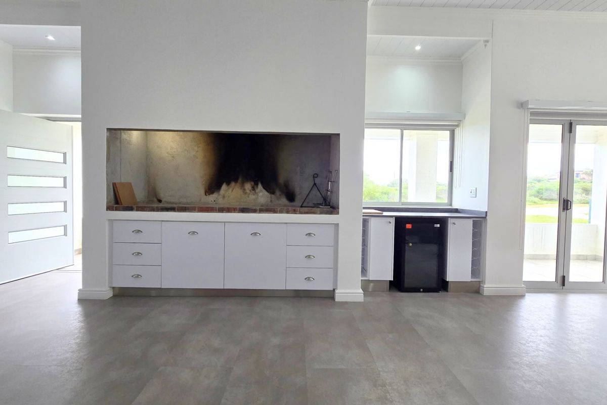Spacious living area featuring a built-in braai, modern cabinetry, and large sliding doors leading to an outdoor space.