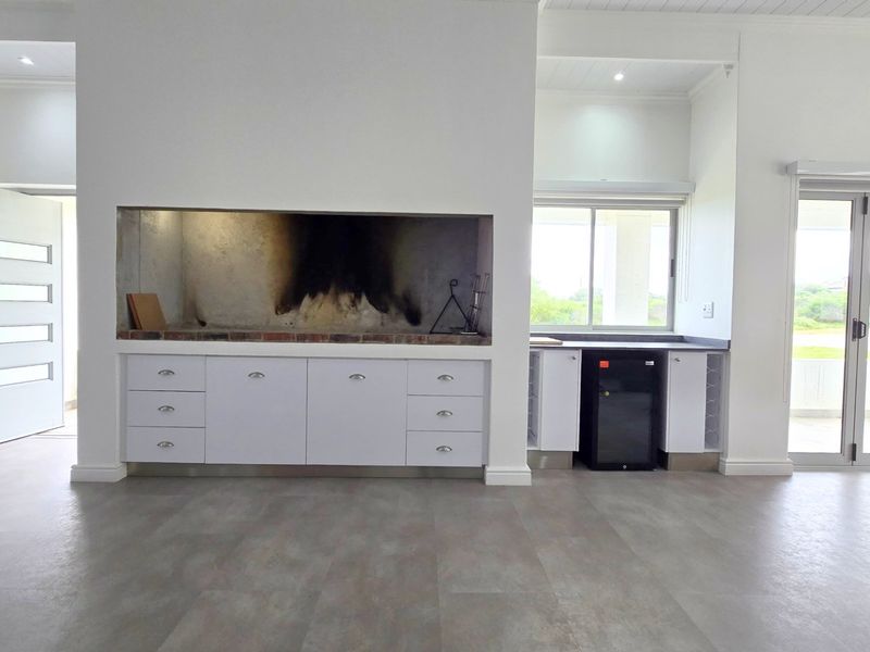 Spacious living area featuring a built-in braai, modern cabinetry, and large sliding doors leading to an outdoor space.